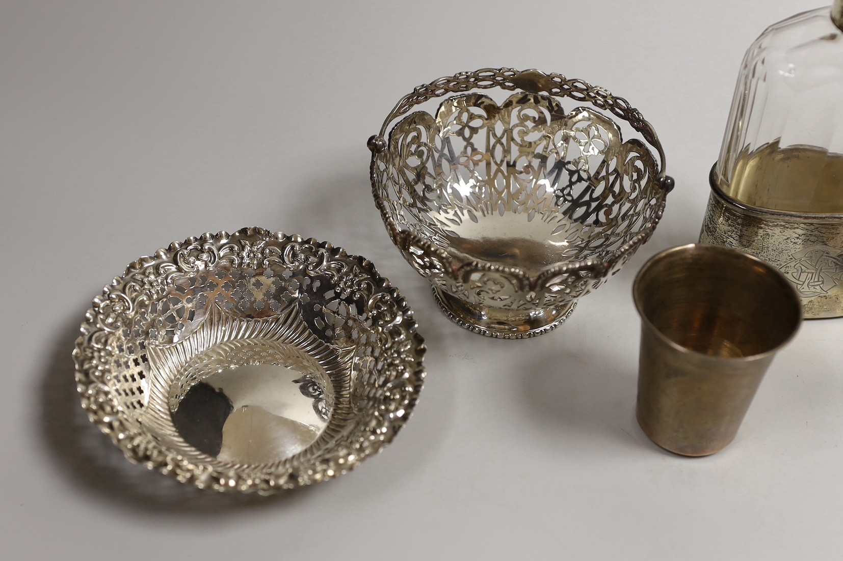 A pair of Edwardian pierced silver bonbon baskets, Nathan & Hayes, Birmingham, 1909, diameter 10.1cm, a pair of silver bonbon dishes, an Edwardian silver mounted glass hip flask, by Charles & George Asprey, London, 1908